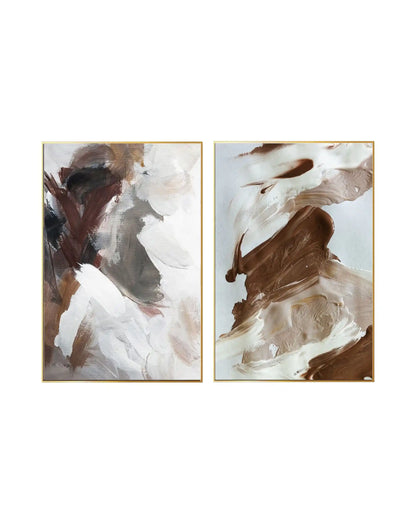 An abstract expressionist diptych featuring heavy, textured brushstrokes in an organic, earthy color palette. The composition blends thick patches of chocolate brown, warm taupe, and creamy beige with stark white highlights on a neutral background. The gestural, layered paint application creates a dynamic sense of movement across both panels, which are enclosed in slim gold frames.