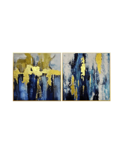 Modern abstract diptych canvas art featuring textured deep navy blue, teal, and gold leaf accents on a white background with gold frames.